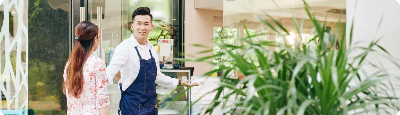 Small business owner greeting a pedestrian passing his store.
