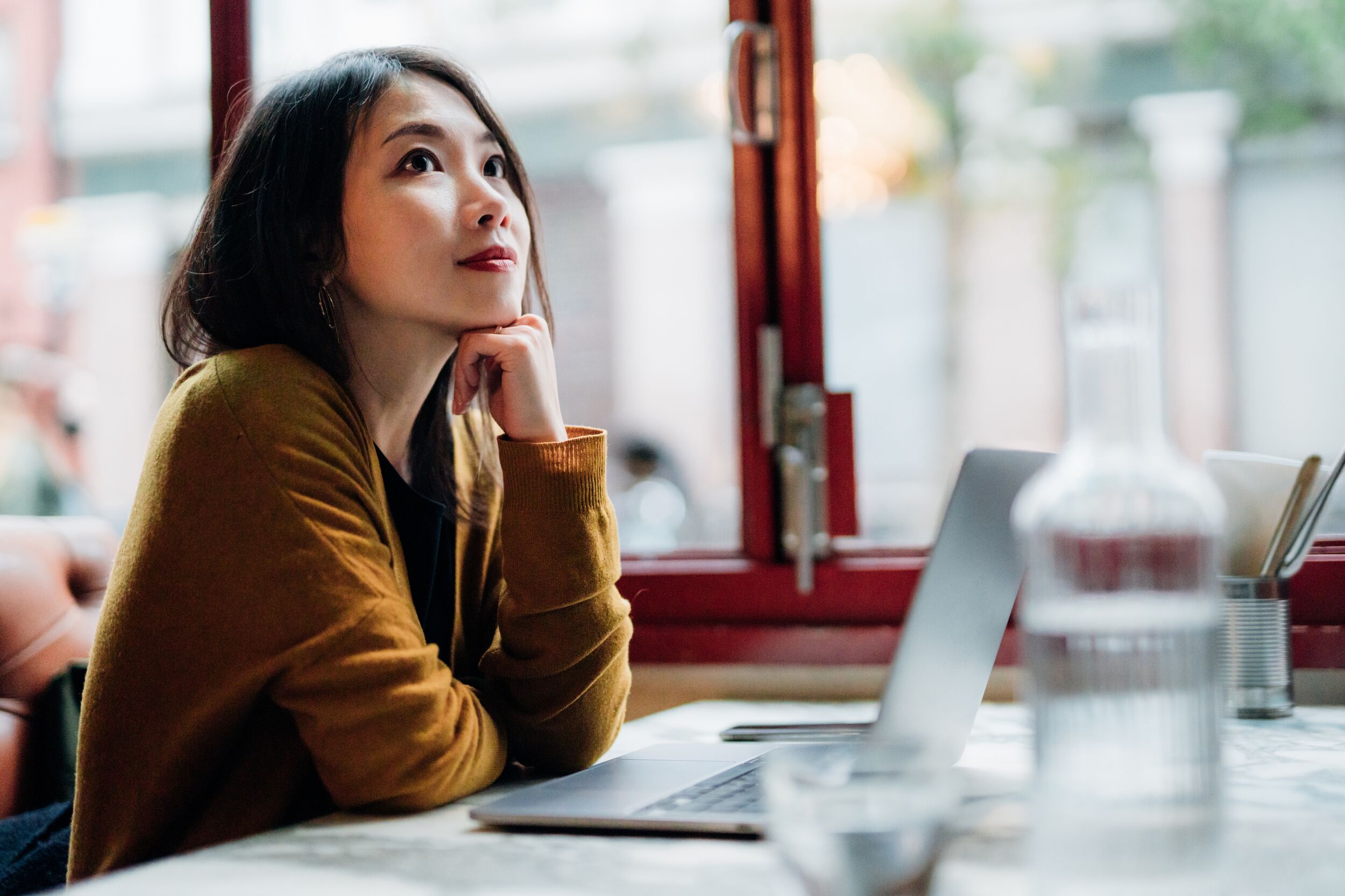 Women over her laptop daydreaming.