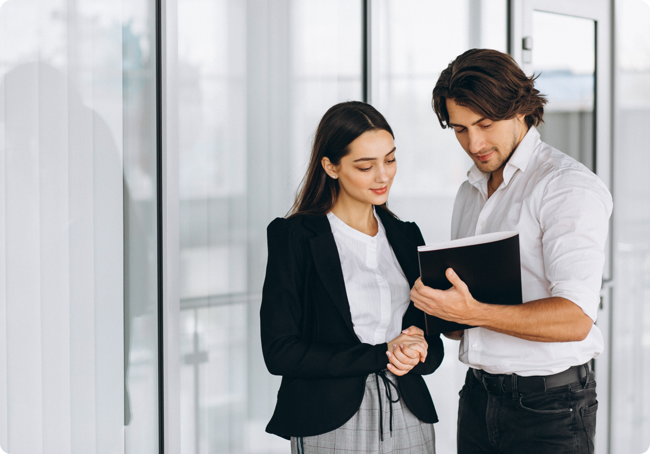 Two people stand as they study a document