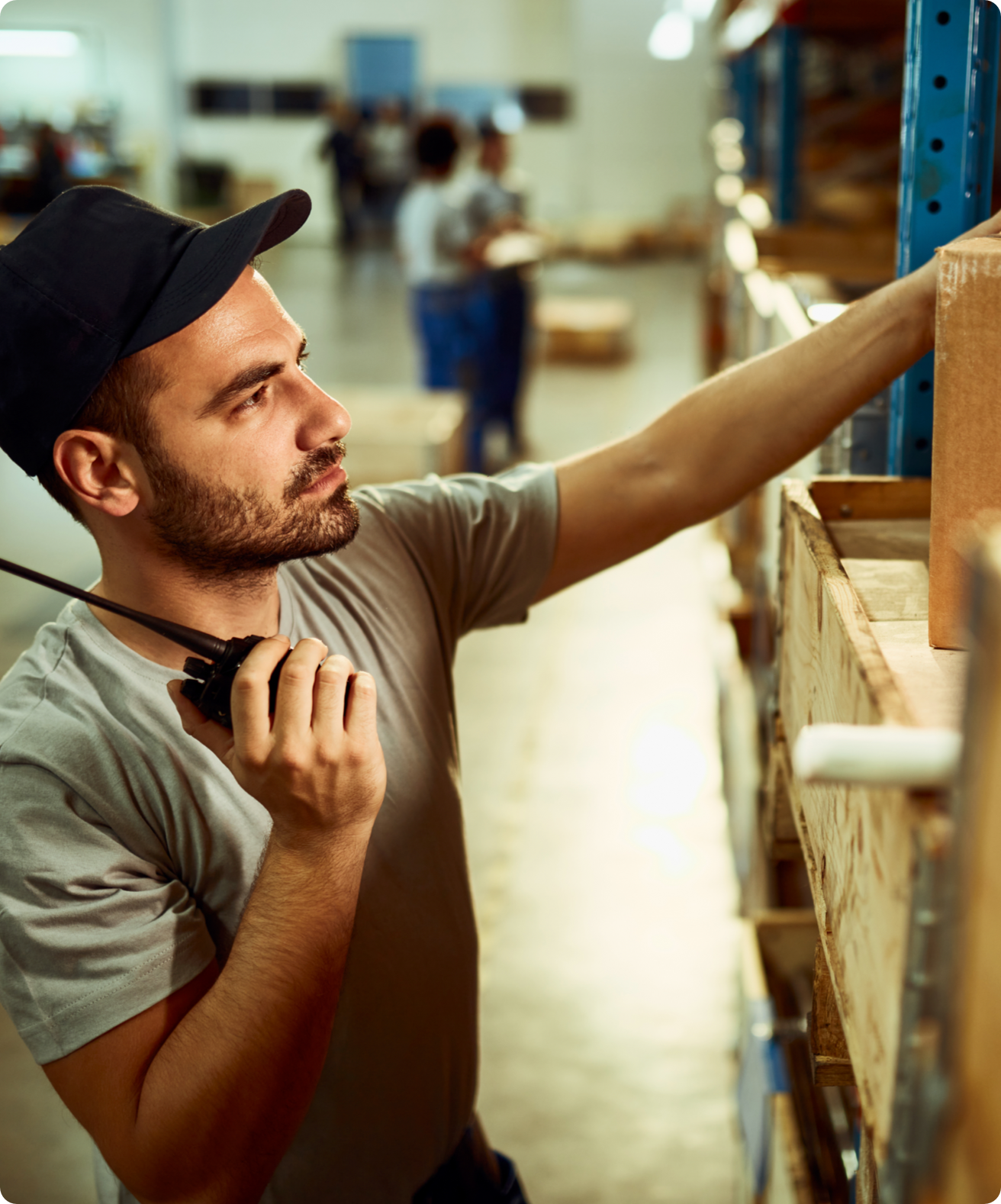 Factory worker wearing a black baseball cap, holding a CB radio.